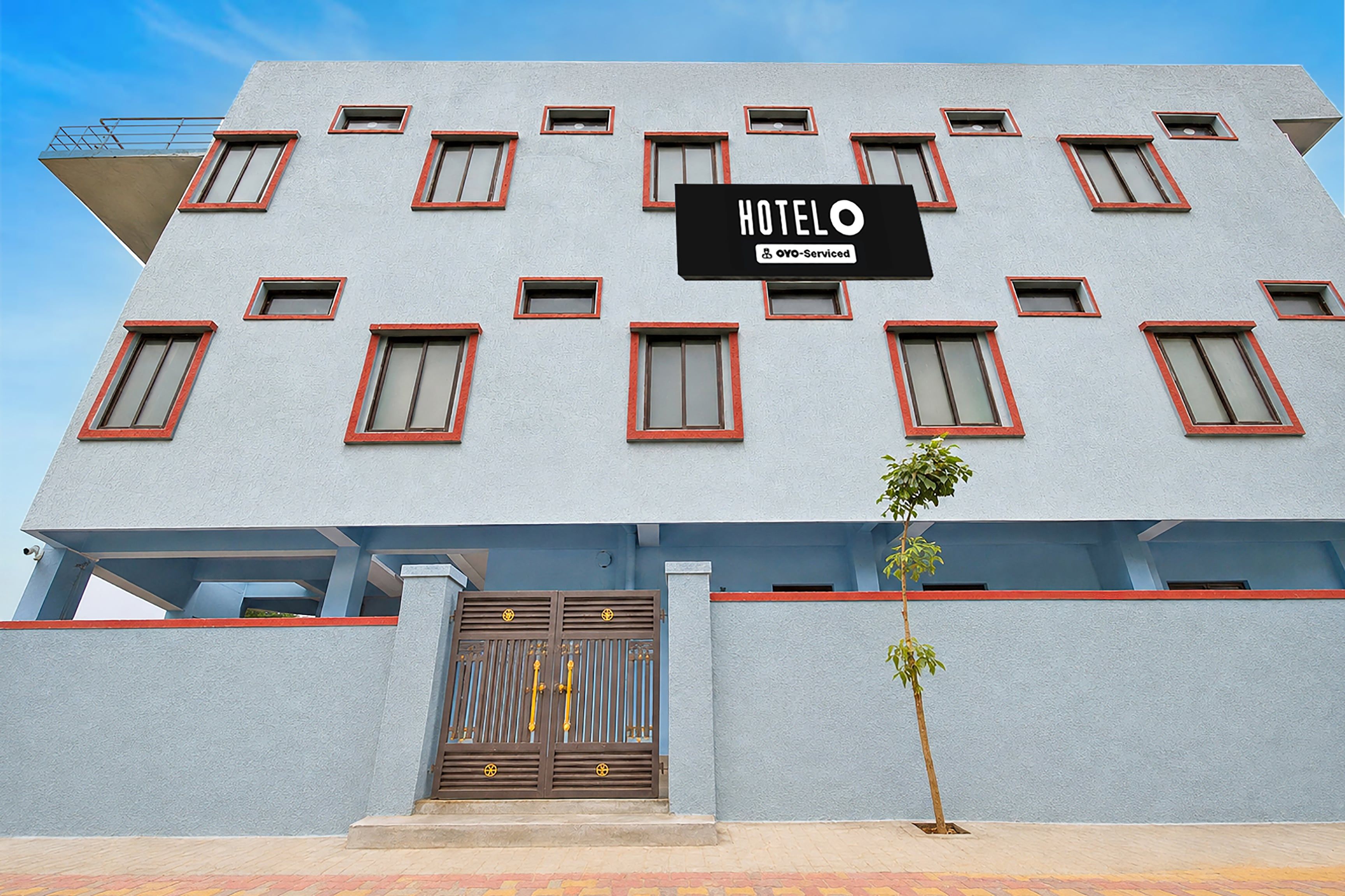 A hotel building with a sign reading 'HOTEL OYO-Serviced' and a gated entrance.