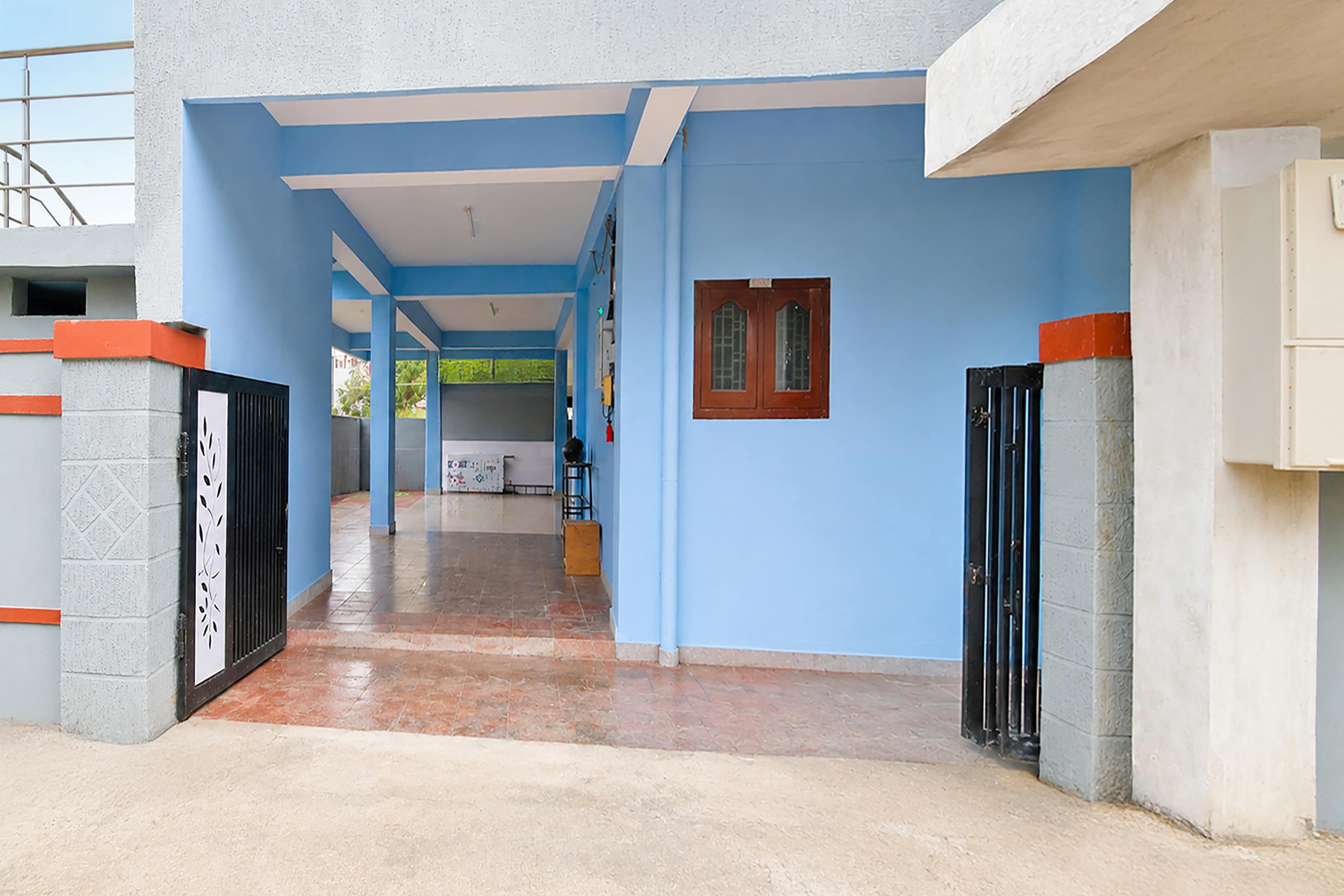 A corridor with blue walls, a tiled floor, and a door with a metal gate.