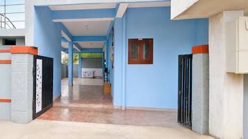 A corridor with blue walls, a tiled floor, and a door with a metal gate.