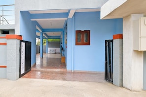 A corridor with blue walls, a tiled floor, and a door with a metal gate.