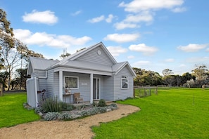 Einbungalow mit Veranda, kleinem Garten und umzäunter Grundstück.
