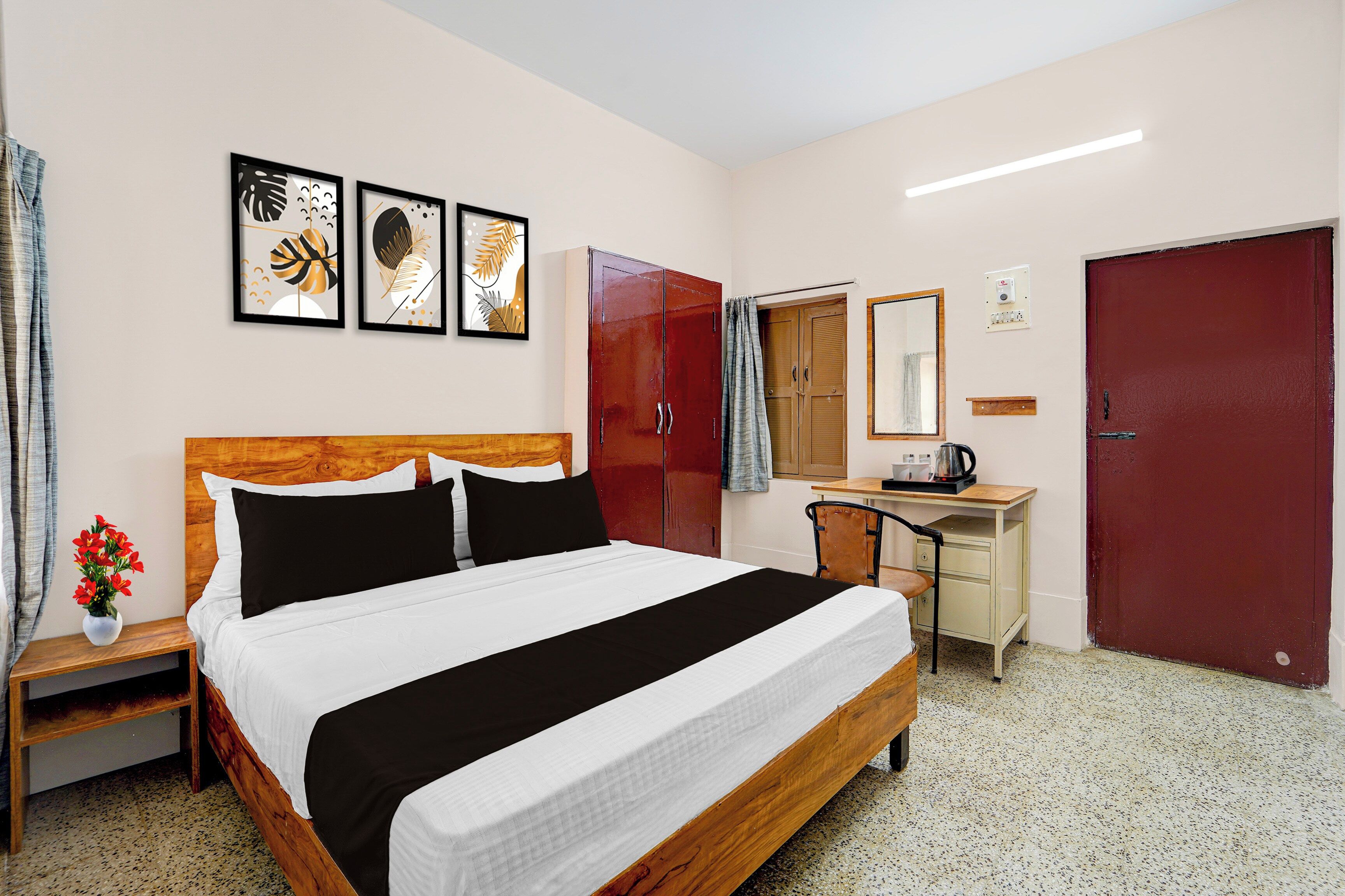 A hotel room with a bed, a desk, a wardrobe, and a mirror.