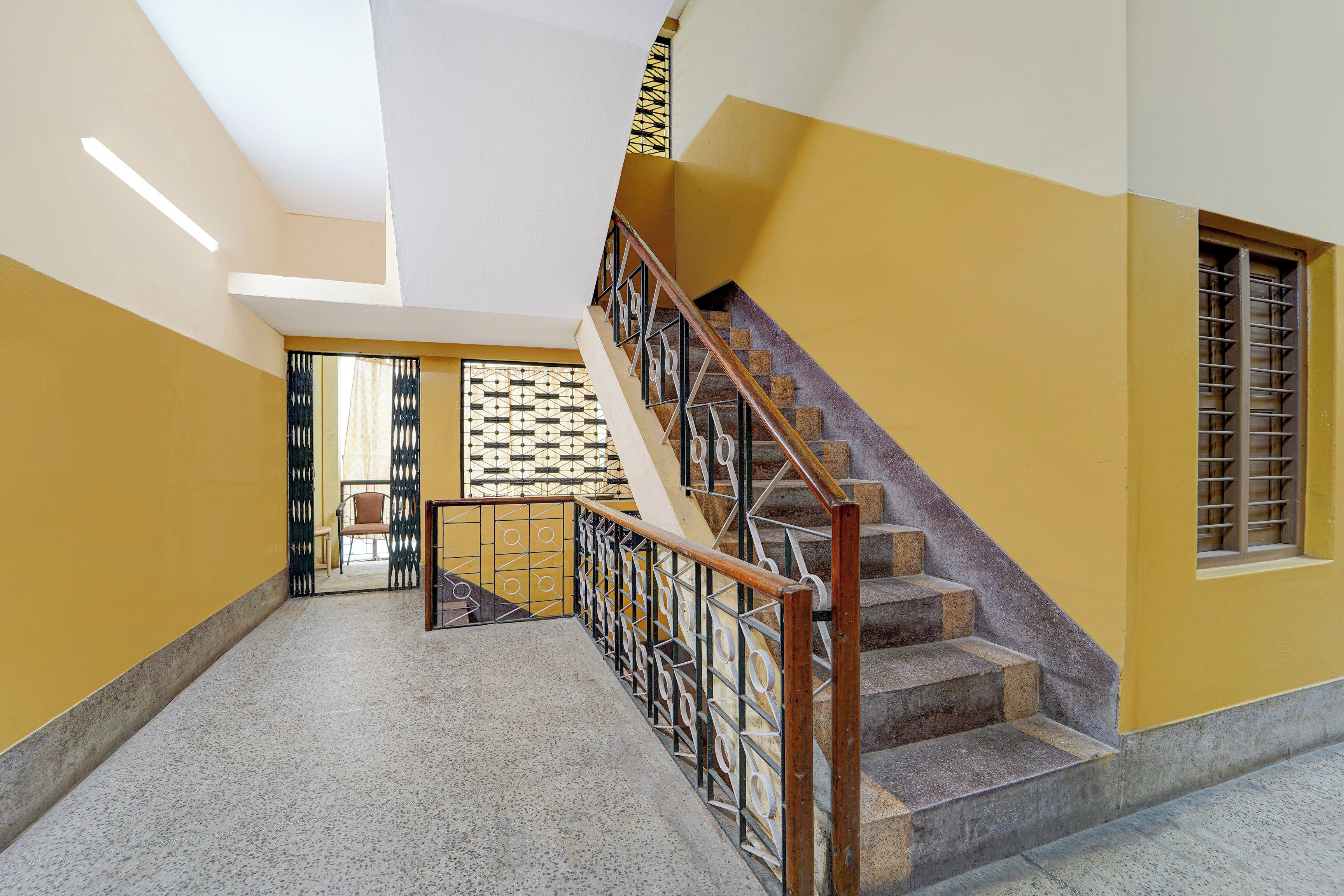 Un escalier avec une rampe, une fenêtre avec des barreaux et une porte ornée d’un portail décoratif.