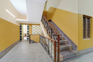 A staircase with a handrail, a window with bars, and a door with a patterned gate. - Super Hotel O Madurai Railway Station (Madurai)