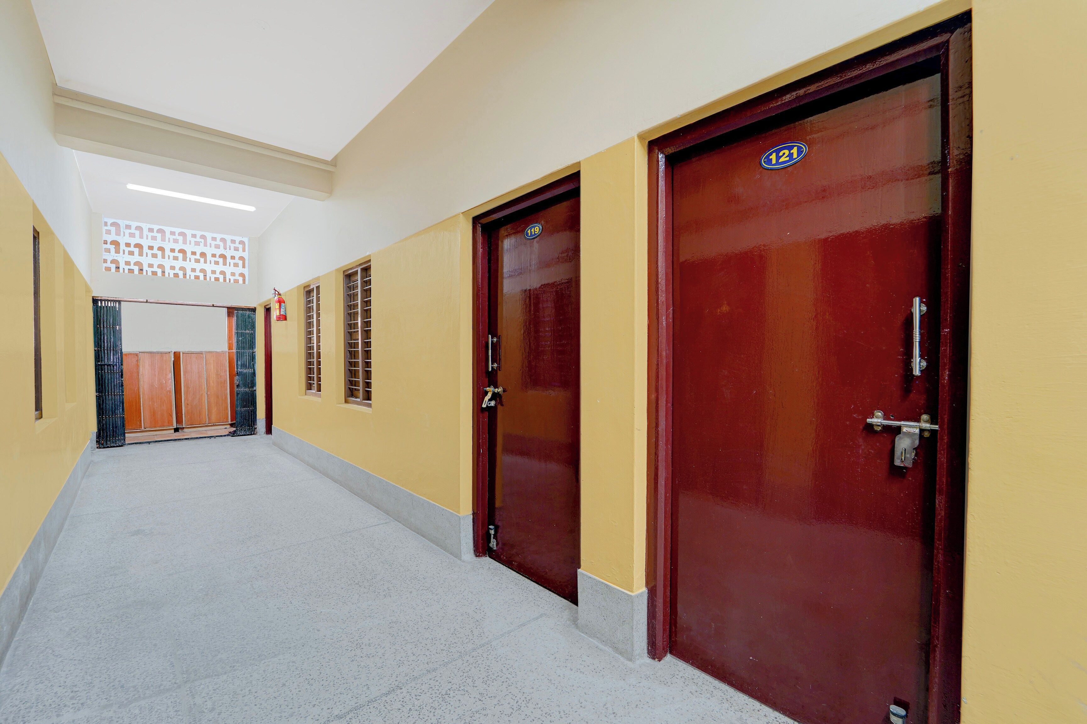 A hallway with doors numbered 119 and 121, a fire extinguisher, and a patterned wall.