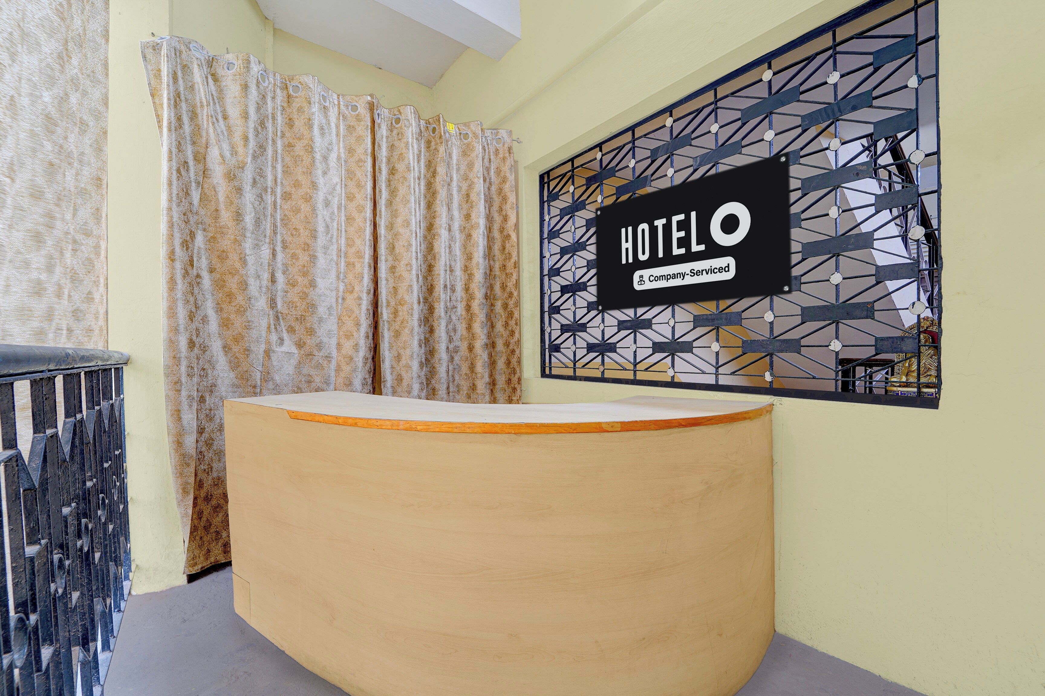 Zona de recepción de un hotel con un mostrador curvo, una cortina estampada y un adorno geométrico en la pared.