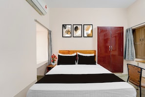 A hotel room with a bed, a wardrobe, a nightstand, a vase with flowers, and wall art. - Super Hotel O Madurai Railway Station (Madurai)