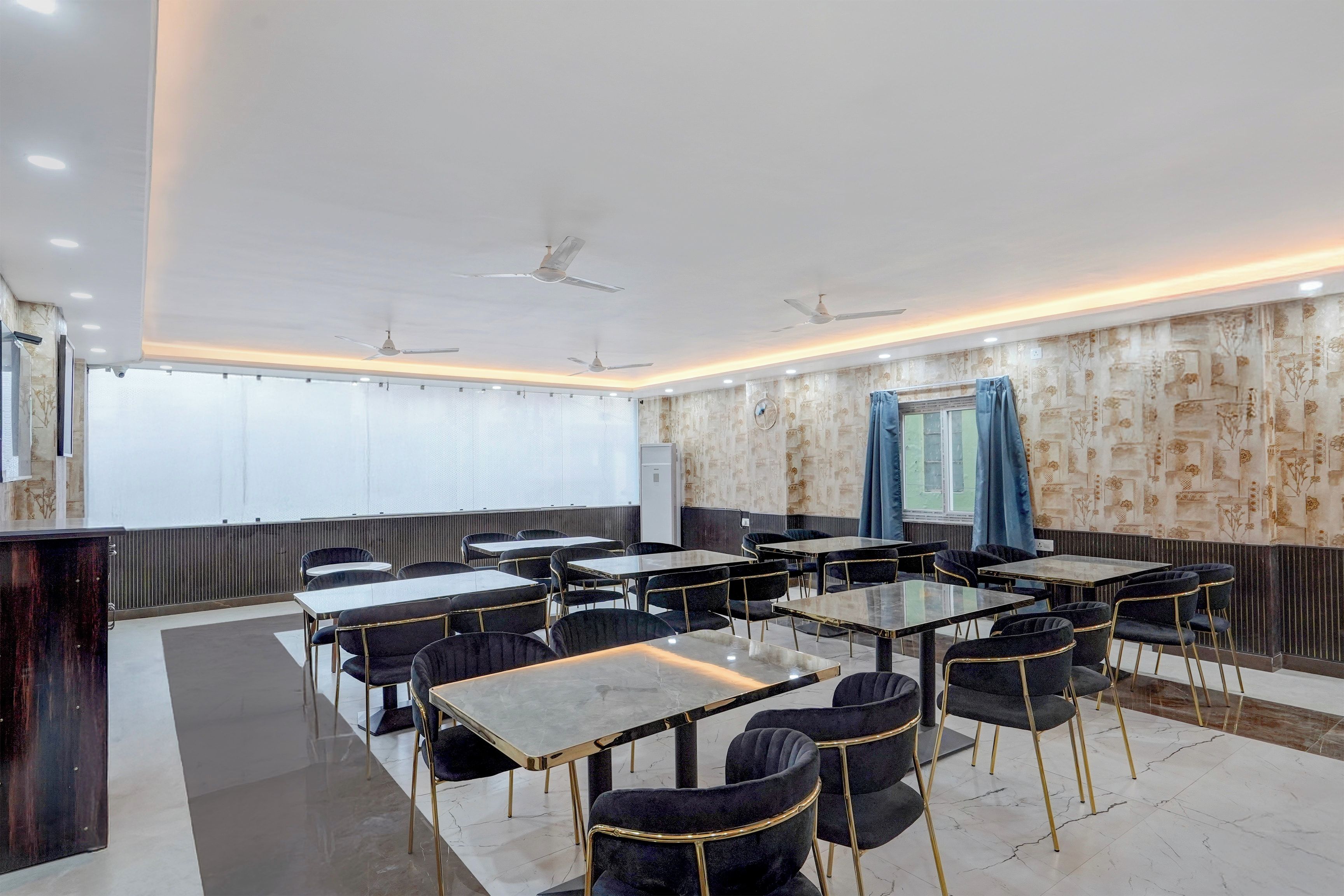 Ein Konferenzraum mit Tischen und Stühlen, Deckenventilatoren und strukturierten Tapeten.