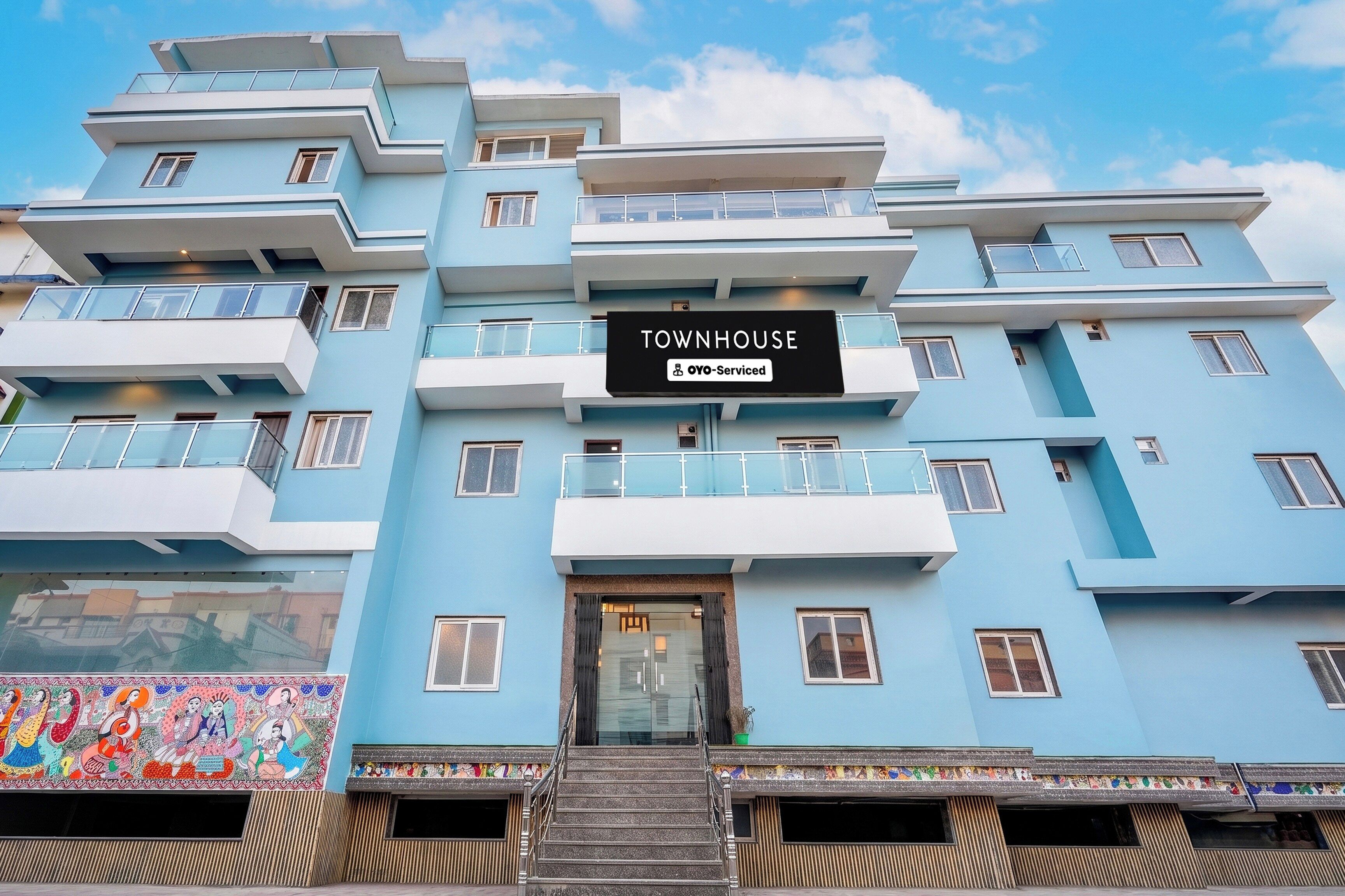 A multi-story building with a sign reading 'TOWNHOUSE' and 'OYO-Serviced'.