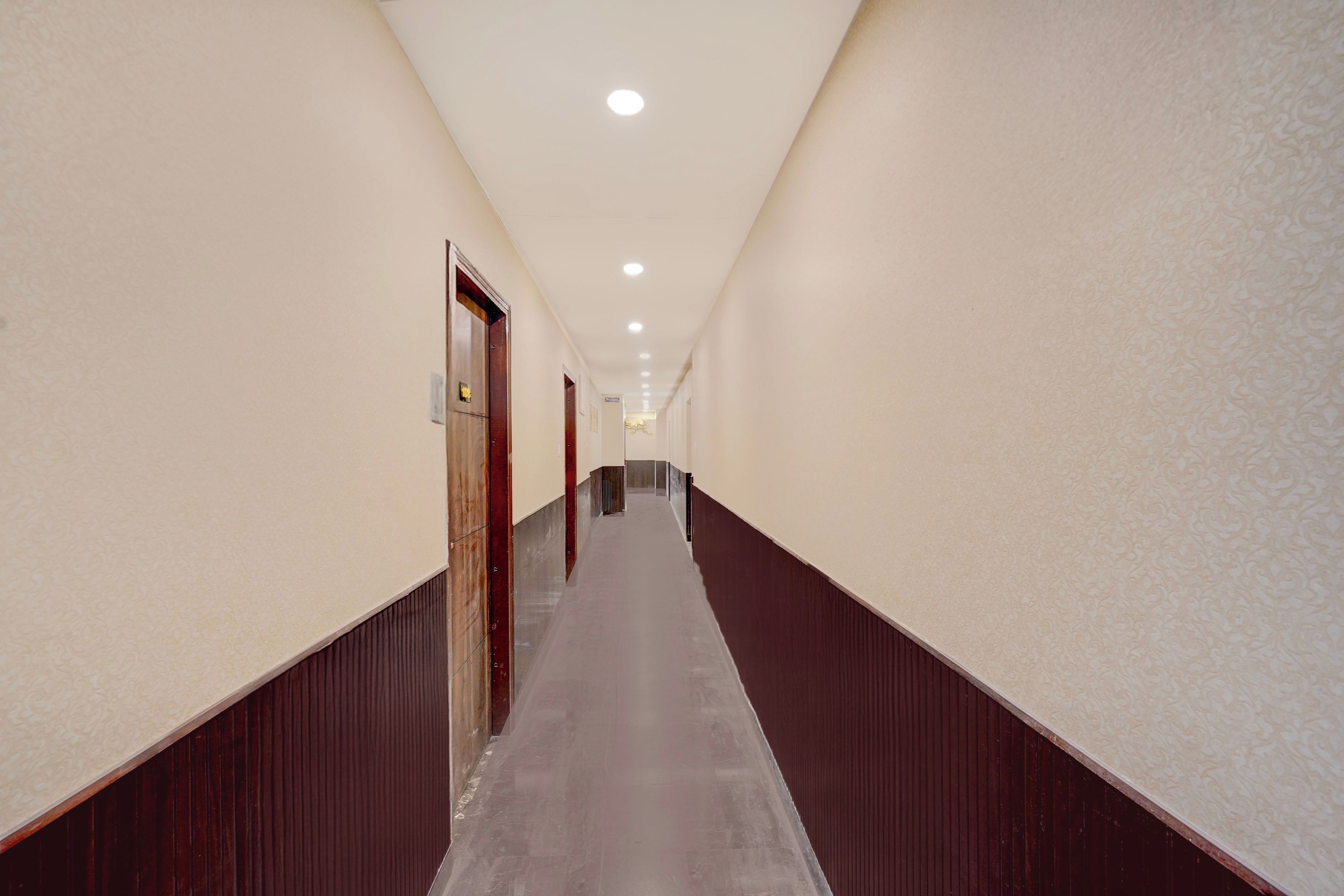 Ein langer, schmaler Hotelgang mit Holzboden und Wänden, der zu einer Tür am Ende führt.