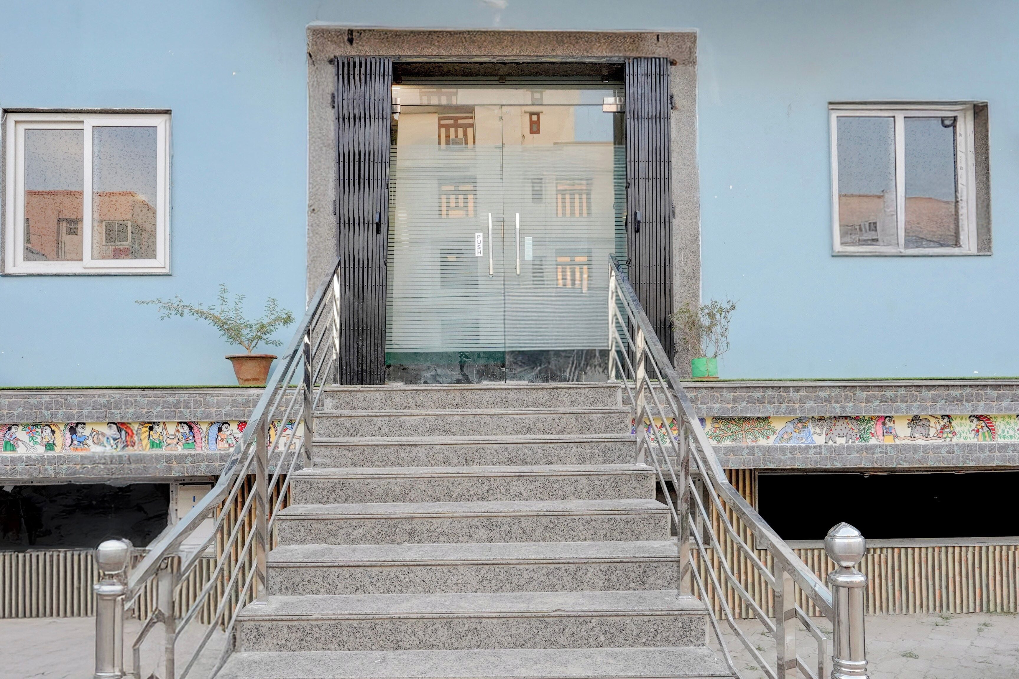 A staircase leading to a building entrance with a metal railing and a door with a push bar.