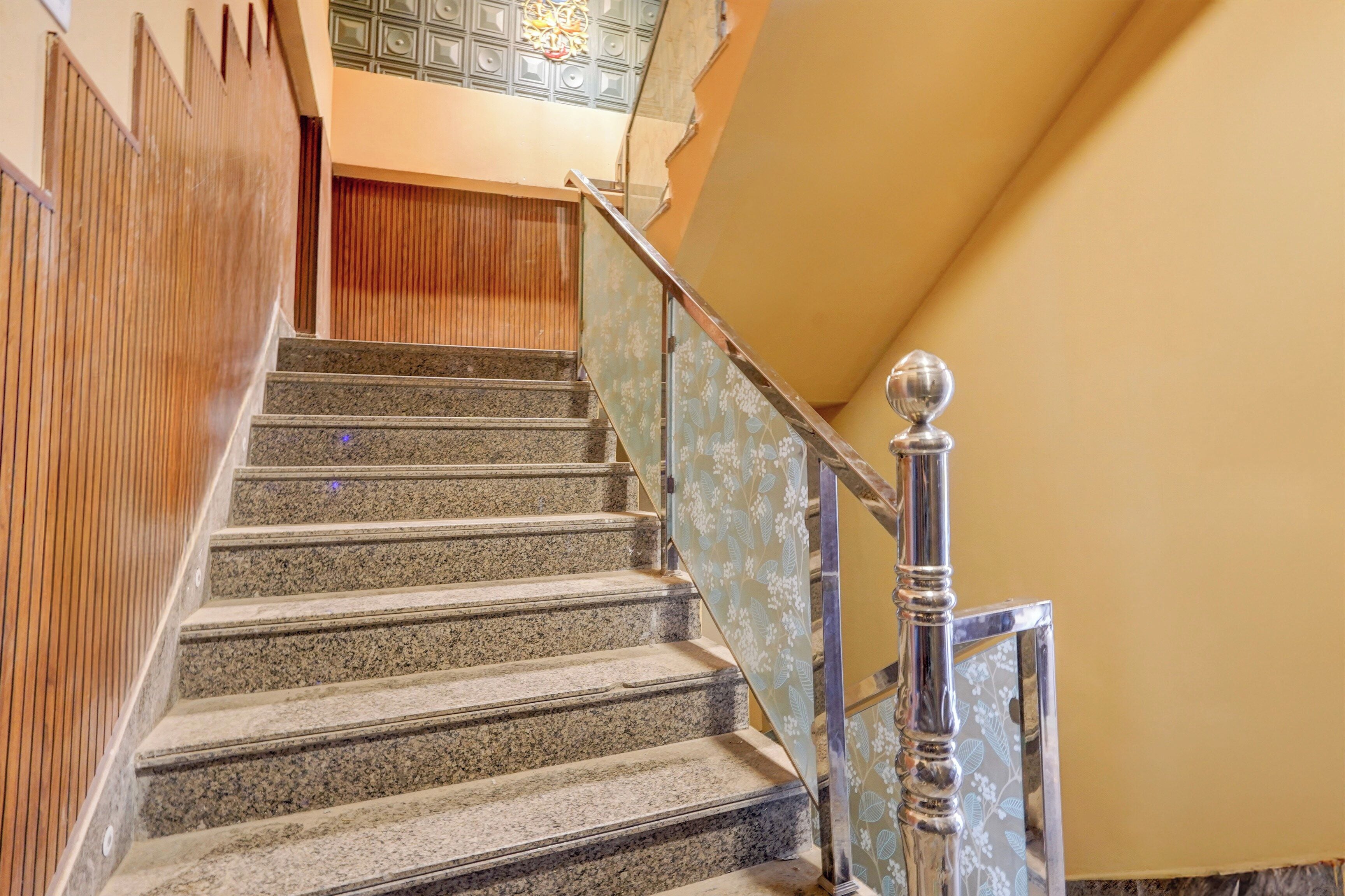 Una escalera con escalones de granito, barandilla de madera y balaustrada de metal.