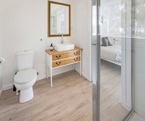 Een badkamer met een wit toilet, een houten wastafelmeubel met lades en een grote spiegel met gouden lijst.