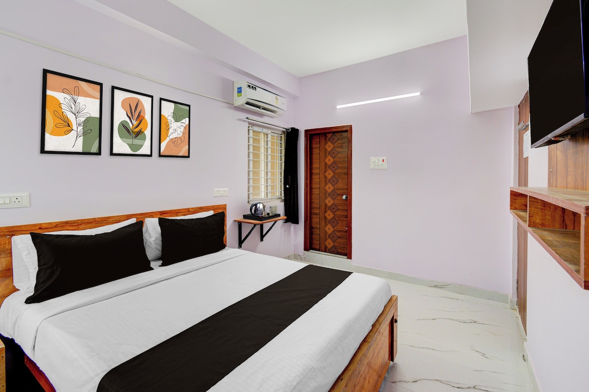 A bedroom with a bed, a television, a window with a curtain, and wall-mounted artwork.