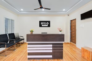 A hotel reception desk with a sign indicating it is OYO-Serviced. There are two chairs and a small plant on the desk. - Hotel O Gandimaisamma Temple Hyderabad (Hyderabad)