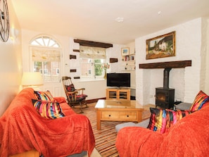 A cozy living room with a fireplace, a television, and a bookshelf. - Stone Cottage (Church Stretton)