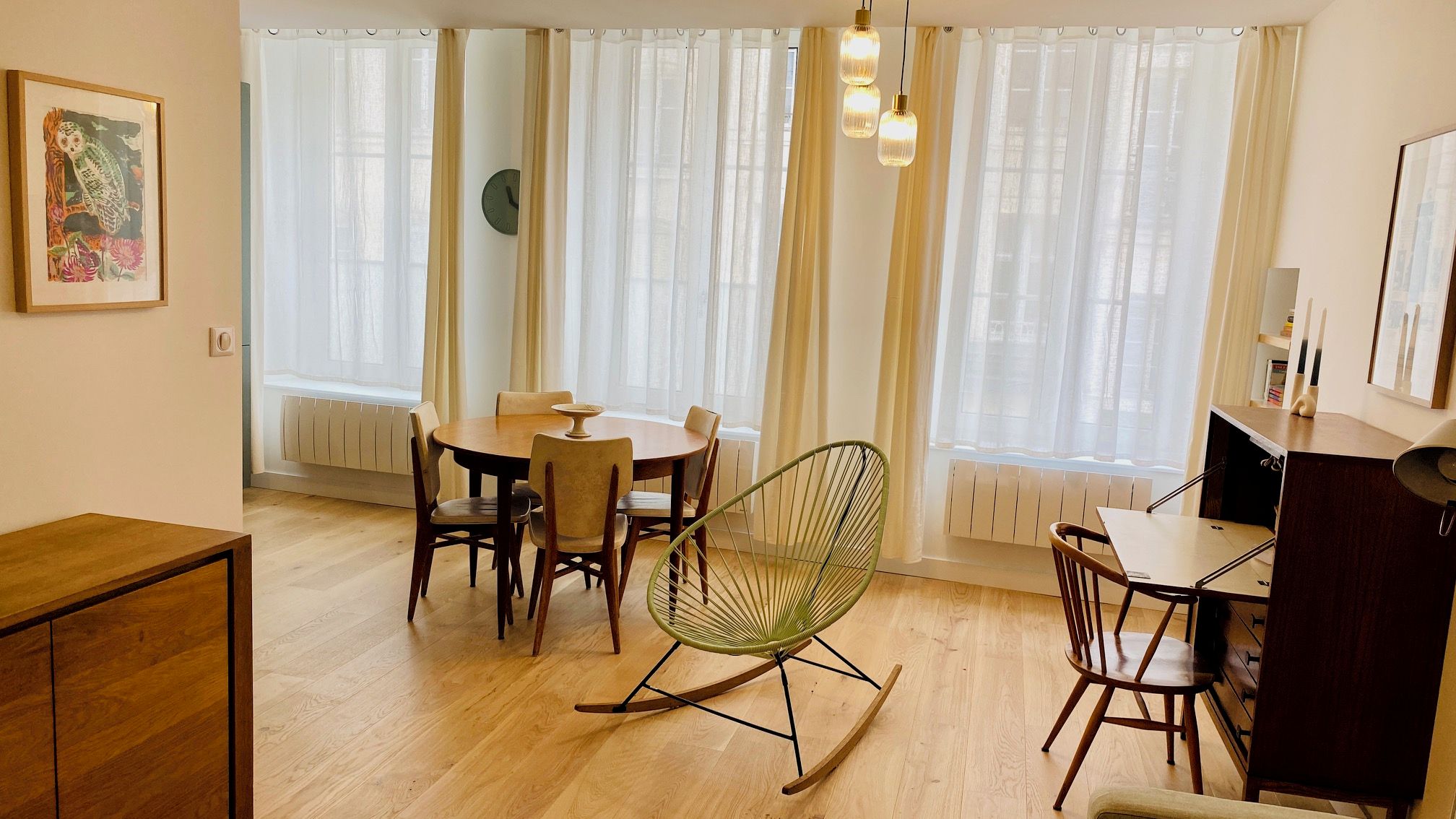 A dining area with a table, chairs, and a green rocking chair.