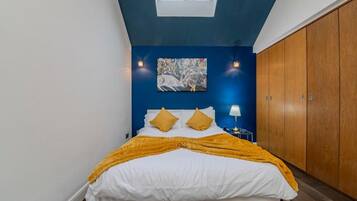 Une chambre à coucher avec un lit, un tableau au mur et une armoire.