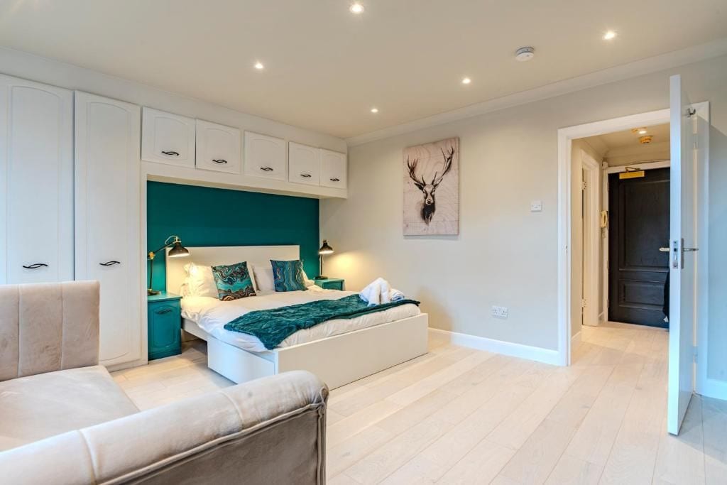 A bedroom with a bed, a nightstand, a chair, and a door leading to another room.