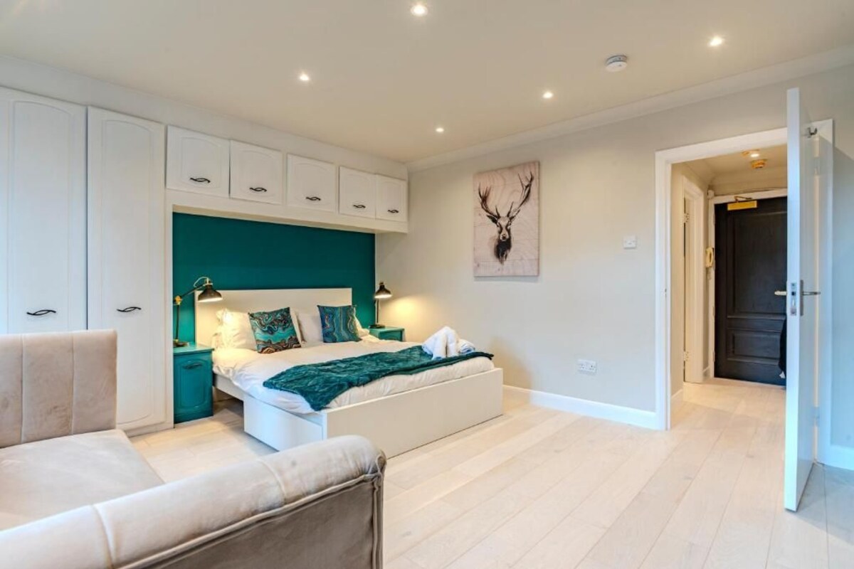 A bedroom with a bed, a nightstand, a chair, and a door leading to another room.