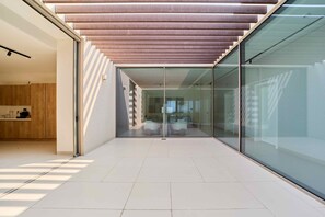 A modern interior with a glass wall, a wooden ceiling, and a tiled floor. - Sleek 4BR Villa | Private Pool & Beach | Al Zorah (Ajman)