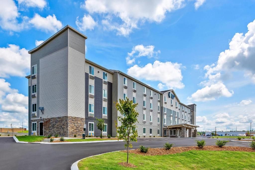 Un hôtel à plusieurs étages, doté d’un design moderne, avec une entrée principale et un espace de stationnement.