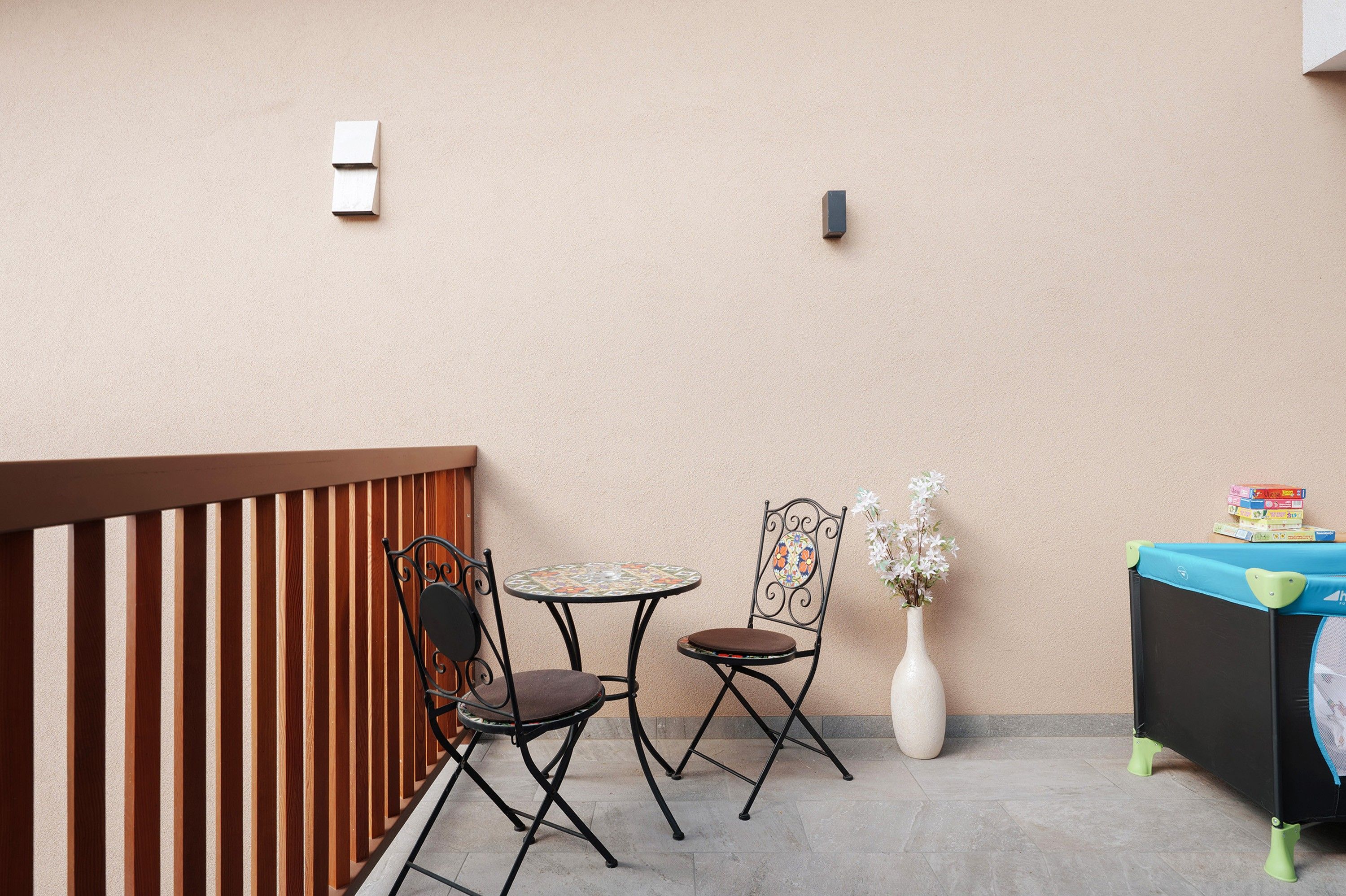 Un balcon avec deux chaises, une petite table, un vase de fleurs et une table avec des livres.