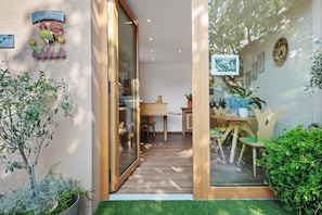 A modern interior with a wooden table and chairs, a glass door leading outside, and a welcome sign with a rooster. - Apartment 'Pfösslerhof Fichte' with Mountain View, Shared Pool and Wi-Fi (Bolzano)