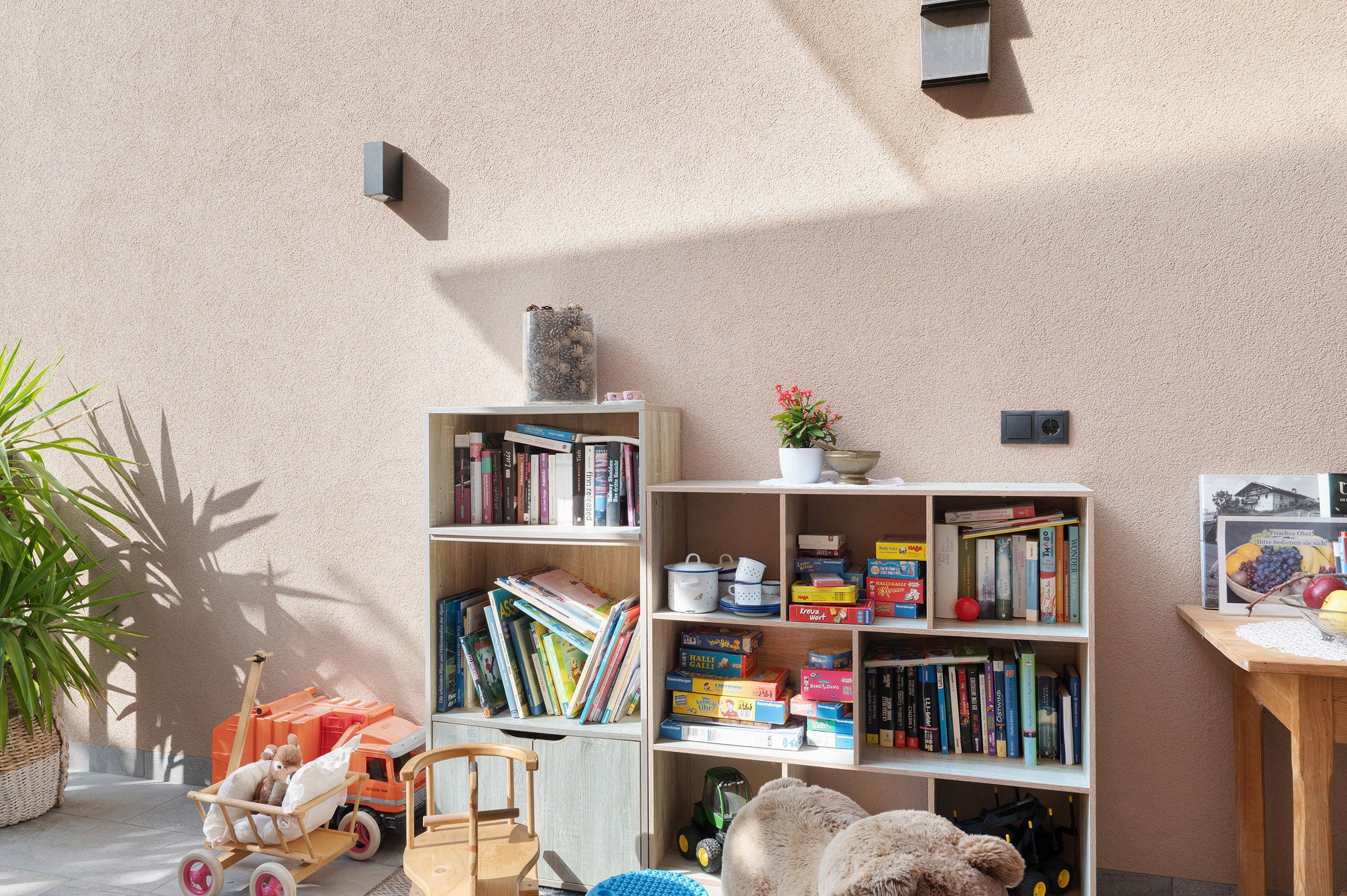 A room with a bookshelf, a small table with a plant, and a toy car.
