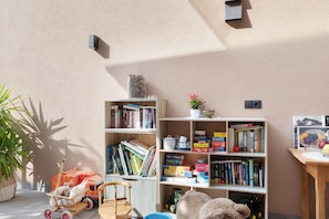 A room with a bookshelf, a small table with a plant, and a toy car. - Apartment 'Pfösslerhof Fichte' with Mountain View, Shared Pool and Wi-Fi (Bolzano)