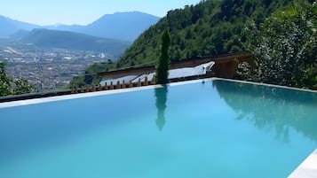 A clear blue infinity pool with a view of a cityscape and mountains in the background.