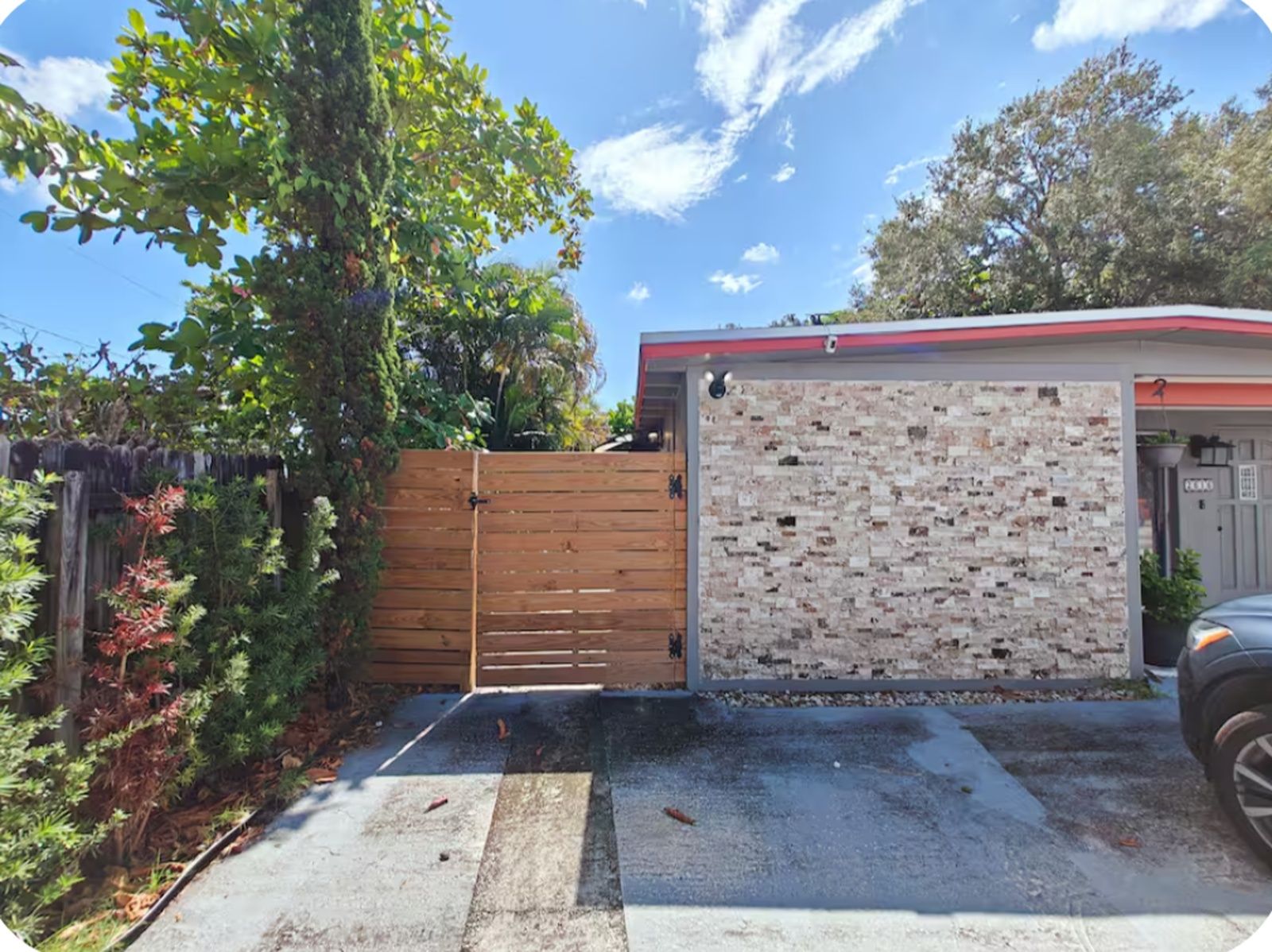 A gated garage with a brick wall, a red roof, and a vehicle parked inside.