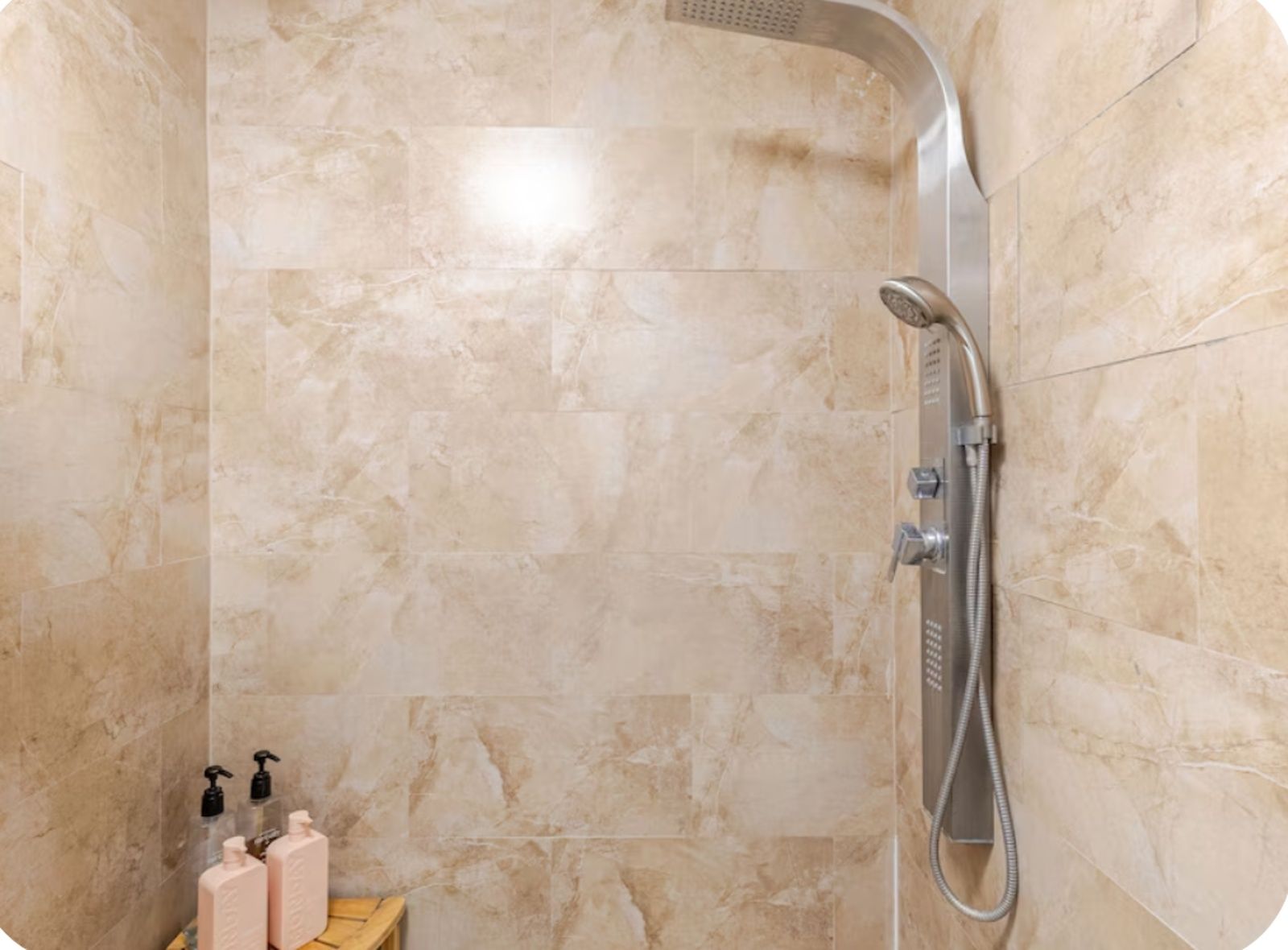 Una ducha con cabezal de ducha de mano y panel de control en la pared.