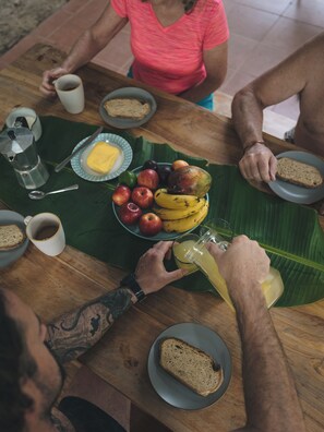 Una mesa de madera con una banana, manzanas y un vaso de jugo.