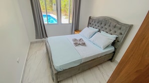 Un dormitorio con cama, ventana y vista a una piscina.