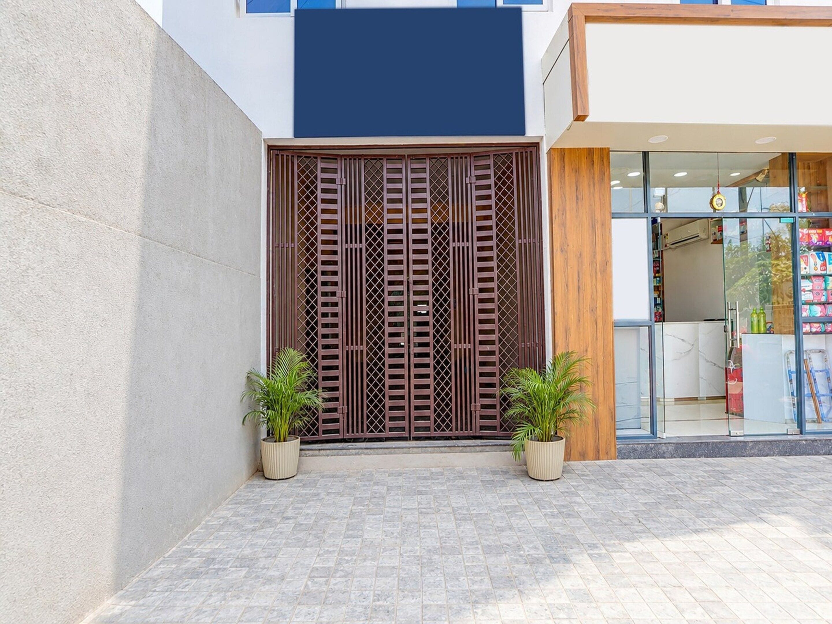 A building entrance with a decorative metal gate, potted plants, and a tiled pavement.
