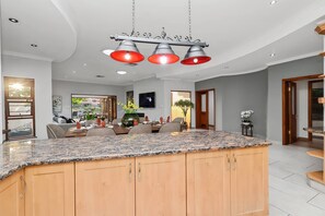 Una cocina moderna con encimera de granito, armarios de madera y una lámpara colgante.