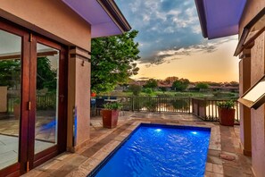A swimming pool with a view of a residential area and a sunset. - Luxurious 4-bedroom Villa With Private Pool in Hartbeespoort (Hartbeespoort)
