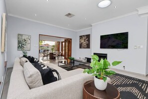 Una sala de estar moderna con sofá, mesa de centro, televisor y un comedor con sillas y mesa.