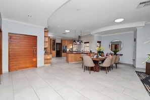A modern kitchen with a central island, dining area with chairs, and a large mirror. - Luxurious 4-bedroom Villa With Private Pool in Hartbeespoort (Hartbeespoort)