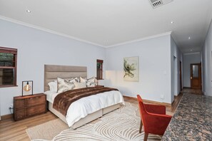 A bedroom with a bed, bedside tables, a chair, a rug, and artwork on the wall. - Luxurious 4-bedroom Villa With Private Pool in Hartbeespoort (Hartbeespoort)