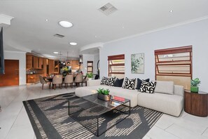 Una sala de estar moderna con un sofá seccional, una mesa de centro y un comedor con una cocina al fondo.