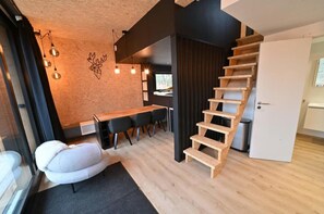 Interior moderno com escada de madeira, área de jantar com mesa e cadeiras, e um sofá.