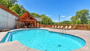 Ein Schwimmbecken mit Liegestühlen und einem Holzpavillon.