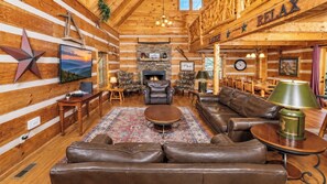 A log cabin interior with a fireplace, leather furniture, and a star decoration on the wall. - Beautiful Log Cabin 3BR, Loft, Games, Hot Tub (Sevierville)