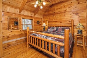 Een slaapkamer in een houten chalet, met een bed, nachtkastje, lamp en raam.