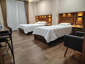 A hotel room with two single beds, a desk, and a chair. - Hotel Central (Cercado)