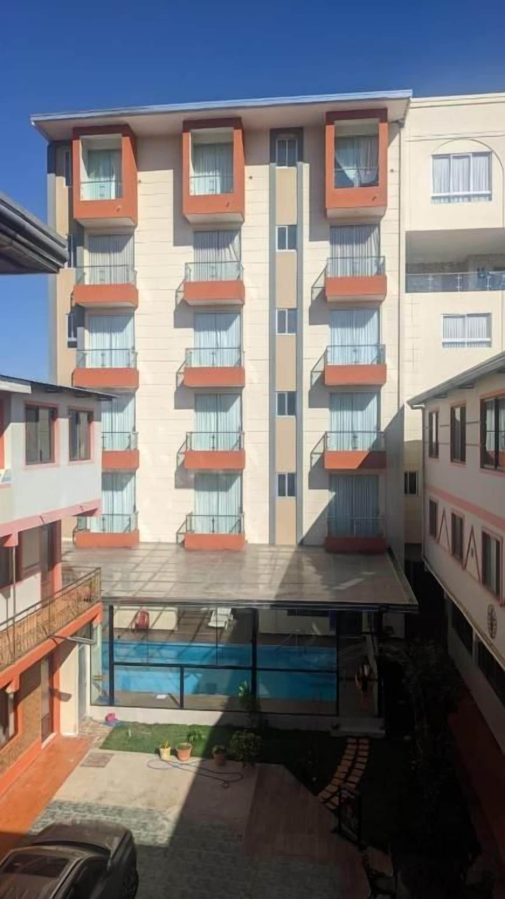 A multi-story building with balconies, a swimming pool, and a courtyard.