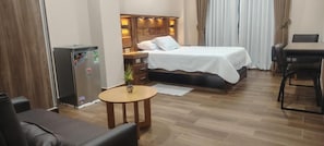 A hotel room with a bed, a small table, a refrigerator, and a dining area. - Hotel Central (Cercado)