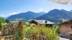 Blick auf eine Berglandschaft mit einer Holzhütte und einem Holzzaun im Vordergrund.